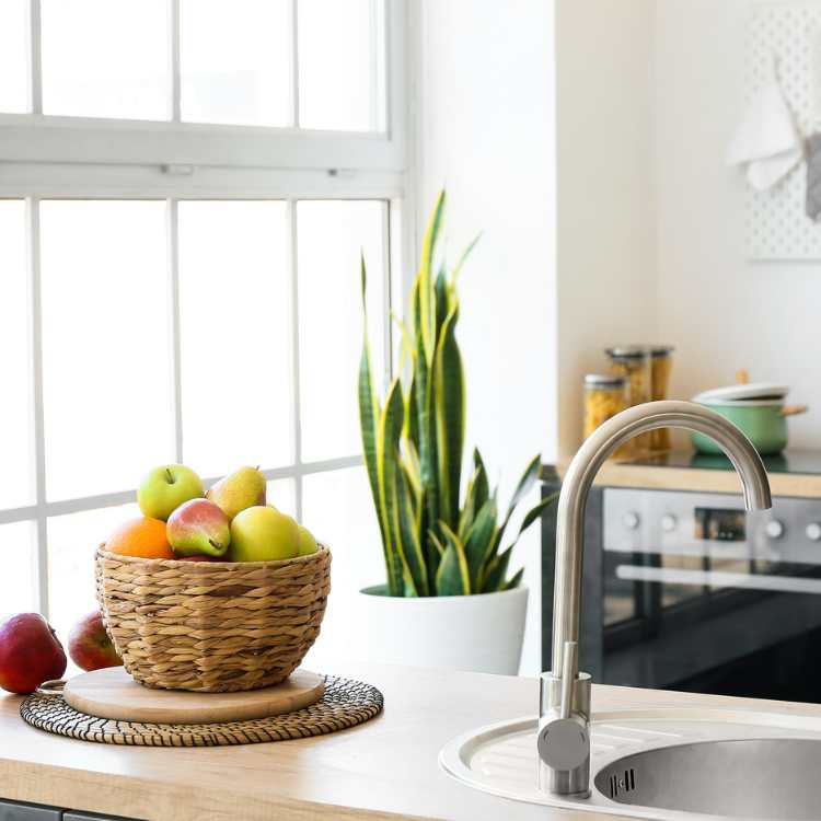 Simple, modern kitchen with wicker basket of fruit by window and sink.